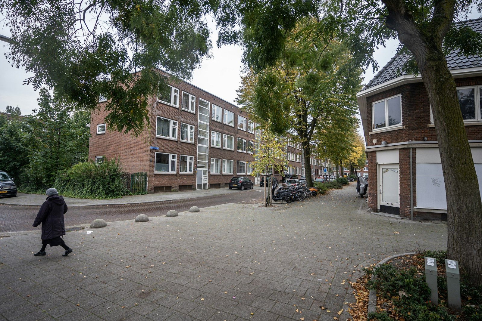 Een straathoek met portiekflats en een vrouw die oversteekt